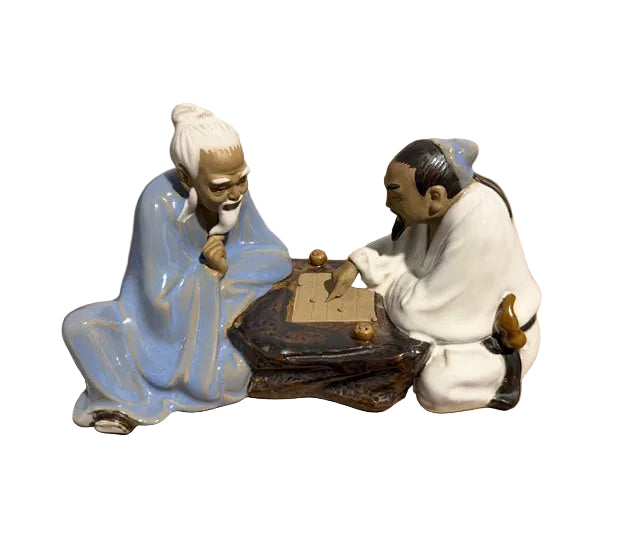Two figurines of elderly men playing a game 