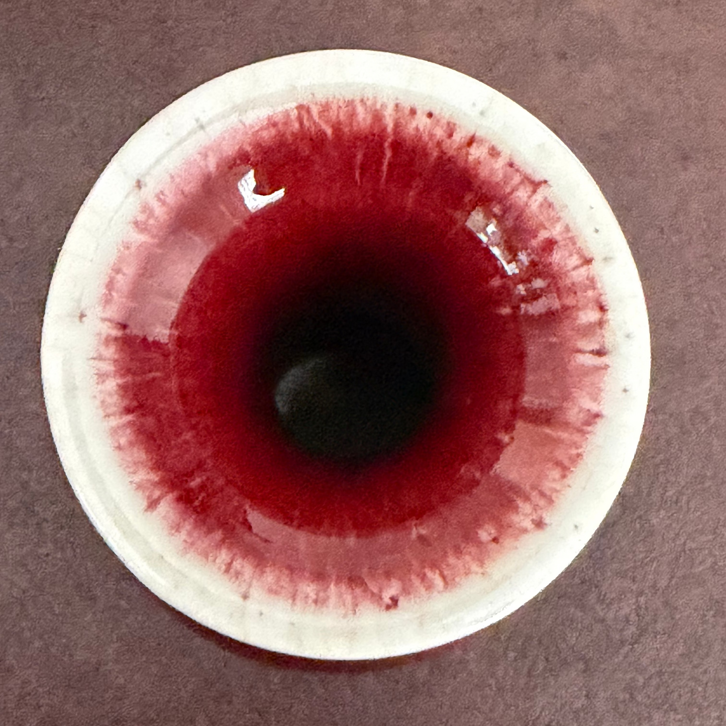 mouth of a red vase with cream glaze on a brown background